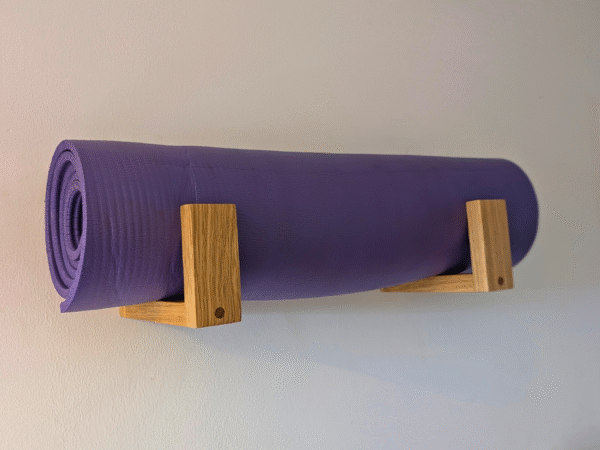 Solid Oak yoga mat hooks - wall mounted close together with mat overhanging, angled view